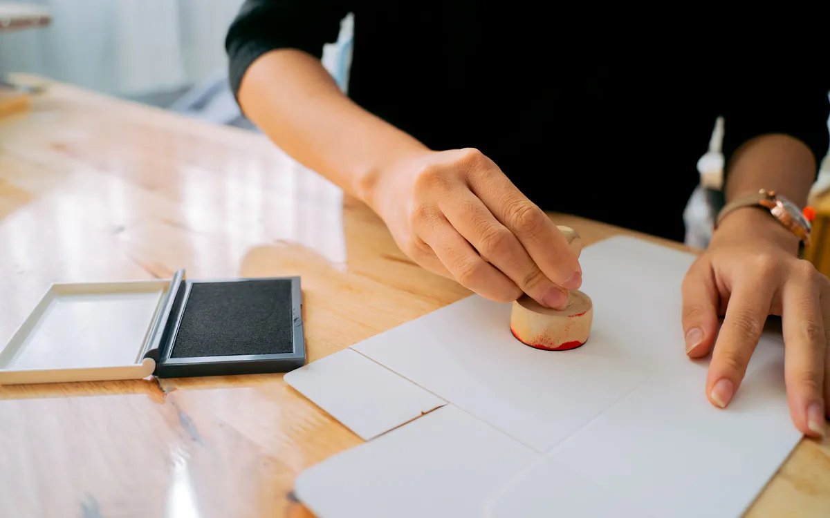Manos sellando un documento sobre un escritorio